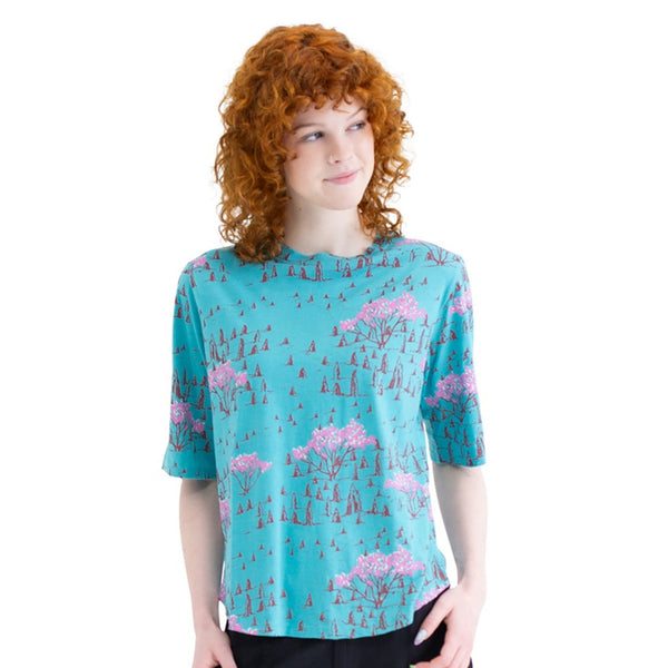 Person wearing a blue t-shirt with pink designs and black pants on a white background