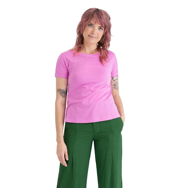Woman wearing a pink t-shirt and green pants on a white background